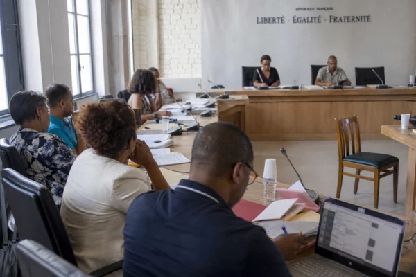 Salle municipale française avec élus anonymes, chaise vide et micros lors d’un débat sur les ingérences numériques