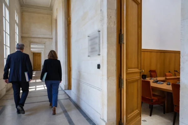 Hall lumineux d’une institution française générique, avec salle d’audition et agents anonymes en arrière-plan