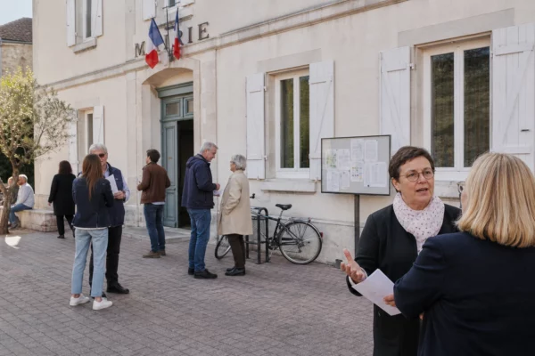 Citoyens anonymes échangeant devant une mairie française lors d’une discussion politique locale