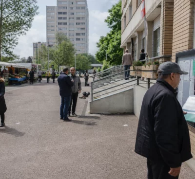 Rue de La Courneuve avec habitants anonymes, marché local et immeubles de logement social en lumière naturelle