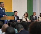 Réunion politique au Brésil dans une salle de convention, avec plusieurs responsables sur scène et un podium de presse.