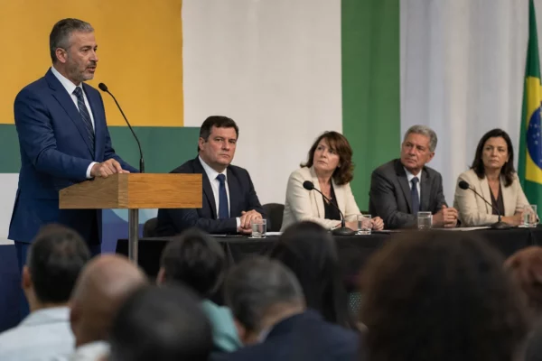 Réunion politique au Brésil dans une salle de convention, avec plusieurs responsables sur scène et un podium de presse.