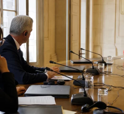 Table de négociation franco-saoudienne avec micros, écouteurs et dossiers dans une salle institutionnelle française