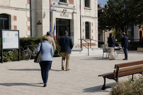Citoyens et élus anonymes devant une mairie française, illustrant les tensions de la vie politique municipale