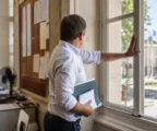 Collaborateur de mairie vu de dos dans un couloir lumineux, dossier en main, en contexte de canicule.