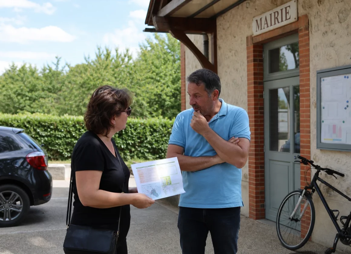 Des habitants échangent avec un agent municipal devant une mairie française sur la prévention des feux de forêt.
