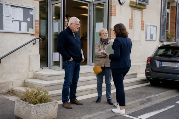 Des habitants échangent devant une mairie de proximité lors d’un débat local sur l’accueil des gens du voyage