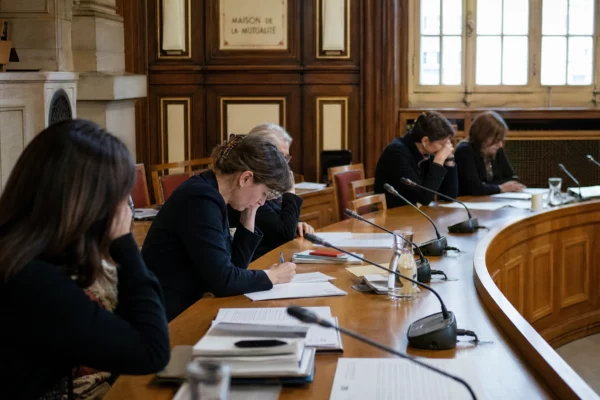 Réunion politique anonyme autour de micros et de dossiers dans une salle Art déco de la Maison de la Mutualité à Paris