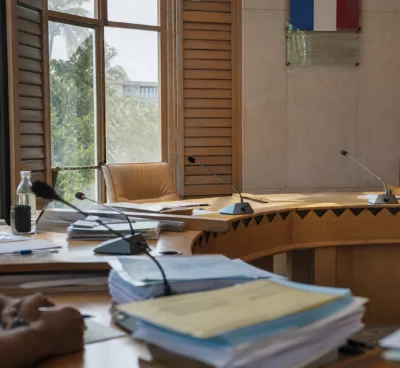 Salle du conseil à Nouméa avec chaise vide, micros et dossiers, dans une ambiance institutionnelle claire et sobre.