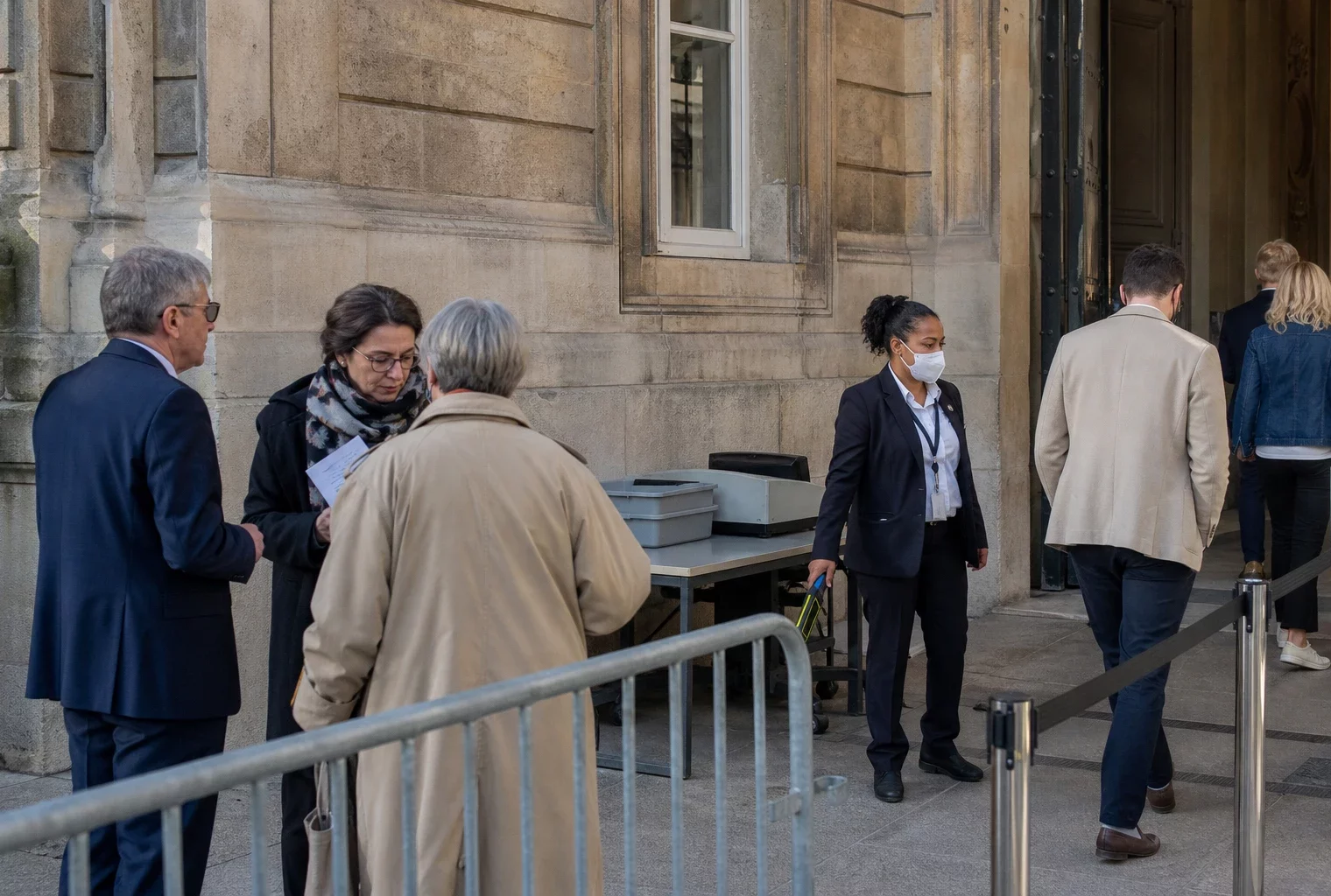 Accès sécurisé calme près du Palais-Bourbon, avec visiteurs anonymes et agents de contrôle à l’entrée.