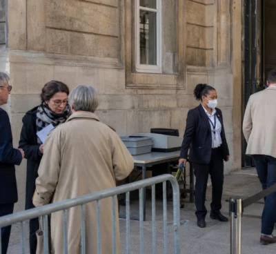 Accès sécurisé calme près du Palais-Bourbon, avec visiteurs anonymes et agents de contrôle à l’entrée.