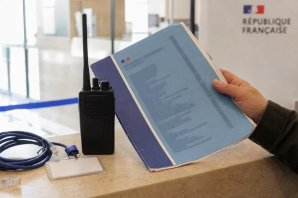 Main tenant un dossier fiscal et un badge d’accès près d’un équipement réseau dans un bâtiment public français