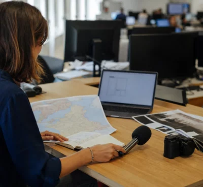 Journaliste préparant un sujet sur le piratage fiscal dans une rédaction française, avec micro et carte floue