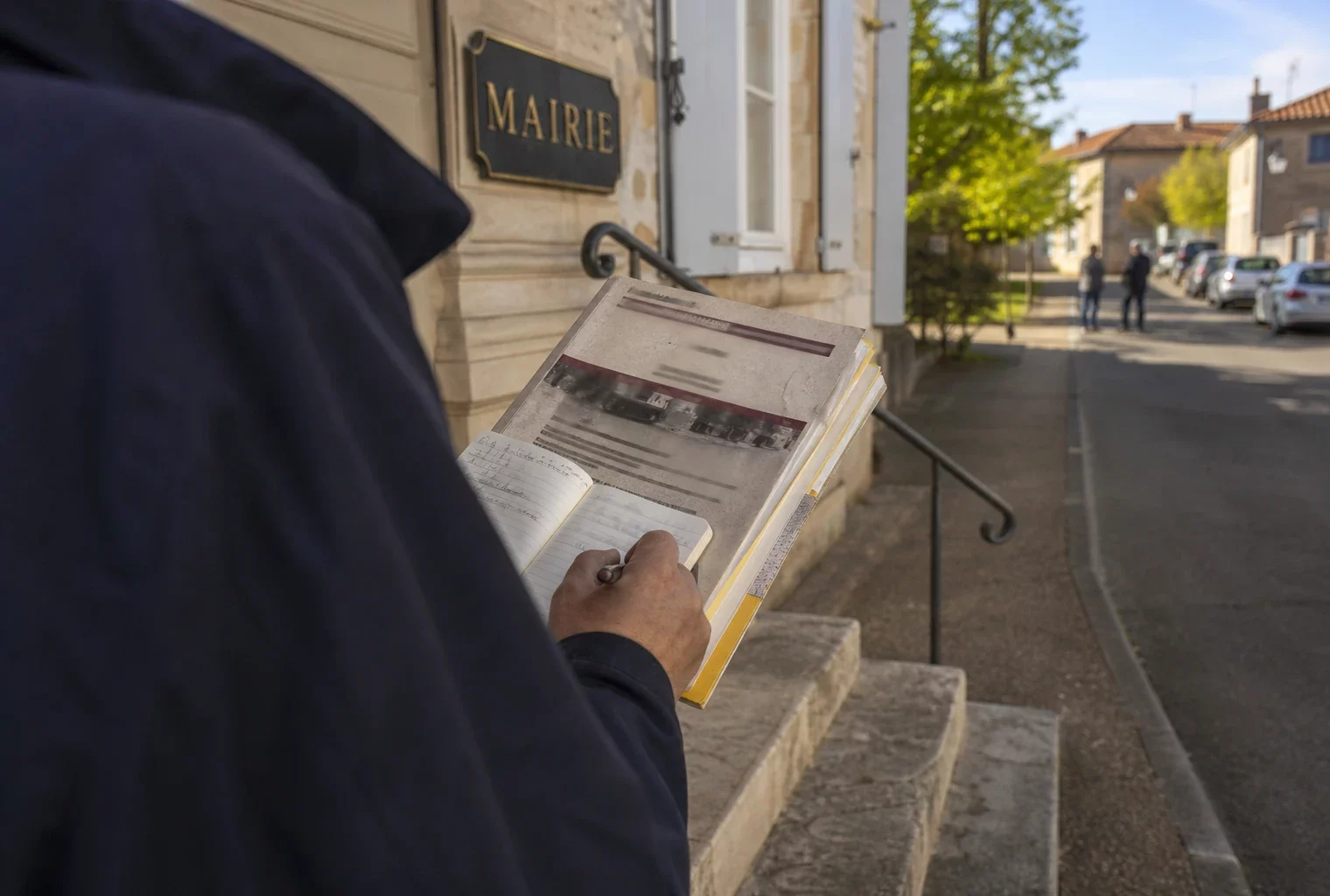 Élu local consultant un dossier sur les pompiers devant une mairie française, dans une lumière douce et naturelle