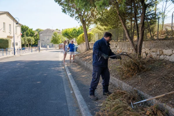Agent municipal débroussaillant une rue près d’une commune française pour prévenir les feux de forêt