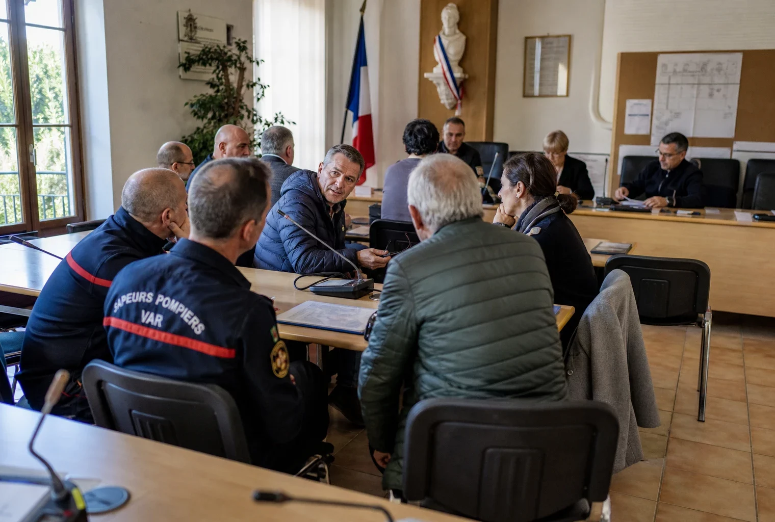 Conseil municipal du Var avec pompiers, micros et chaise vide lors d’une réunion sur la prévention des incendies