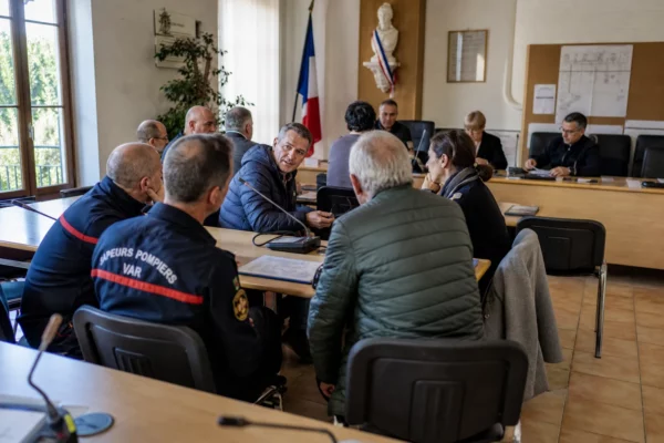 Conseil municipal du Var avec pompiers, micros et chaise vide lors d’une réunion sur la prévention des incendies
