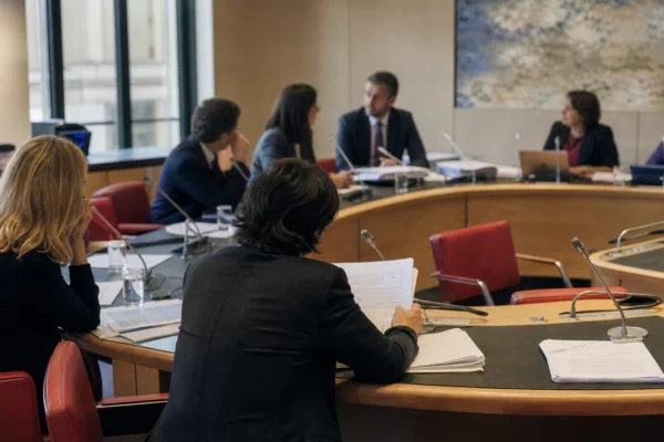 Réunion de commission parlementaire française avec élus anonymes, micros et dossiers autour d’une primaire présidentielle