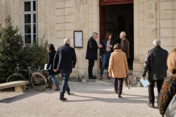 Citoyens anonymes échangeant sur le parvis d’une mairie française lors d’une réunion politique locale