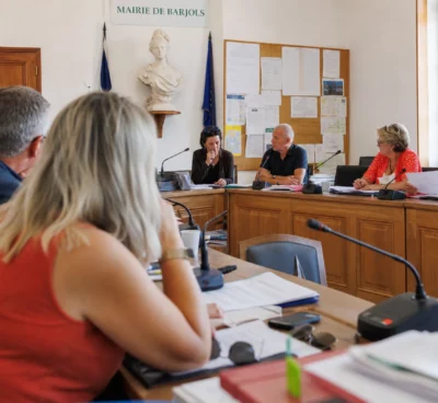 Réunion municipale à Barjols sur la reconstruction après l’incendie, avec micros, dossiers et une chaise vide