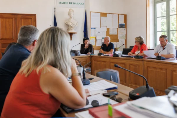 Réunion municipale à Barjols sur la reconstruction après l’incendie, avec micros, dossiers et une chaise vide