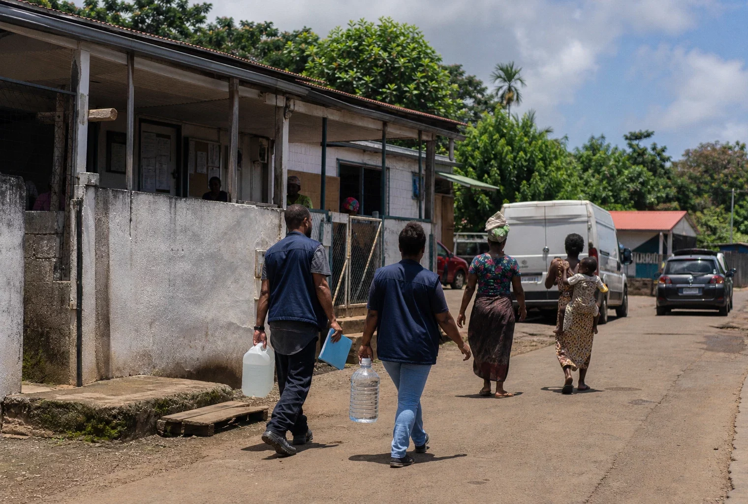 Habitants et bénévoles dans une rue de Mayotte, près d’un équipement public marqué par les retards de reconstruction