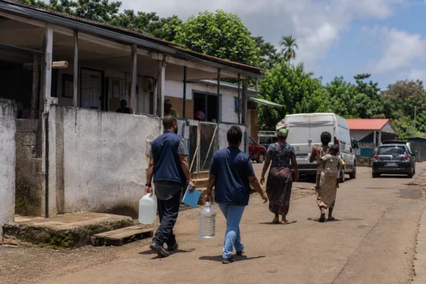 Habitants et bénévoles dans une rue de Mayotte, près d’un équipement public marqué par les retards de reconstruction