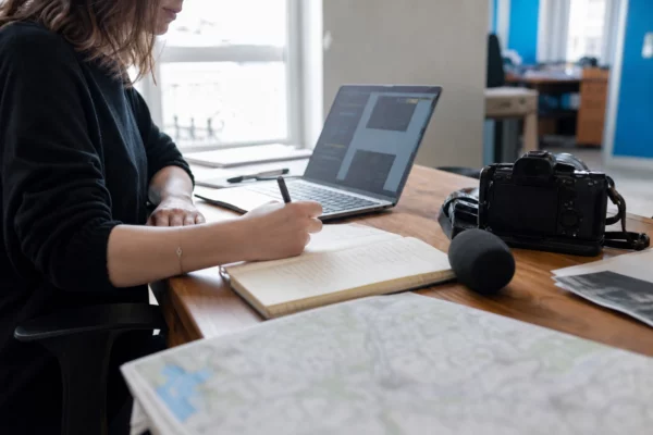 Journaliste en rédaction préparant un sujet sur le climat avec carnet, carte floue et micro sans logo.