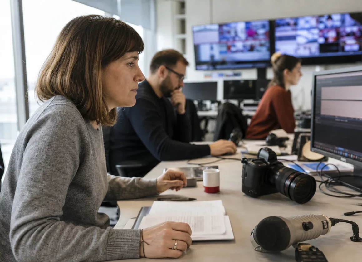 Une rédaction française lumineuse avec journalistes, micros et écrans flous autour d’un sujet de désinformation.