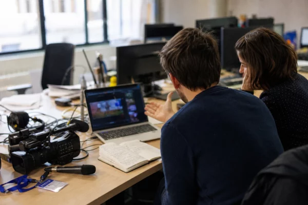 Journalistes anonymes vérifiant une vidéo politique manipulée dans une rédaction française lumineuse