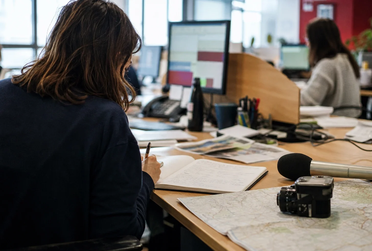 Journaliste préparant un sujet sur l’école dans une rédaction locale française, avec carnet, carte et micro sans logo