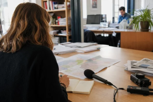 Journaliste préparant un sujet sur un sondage présidentiel dans une rédaction locale française lumineuse