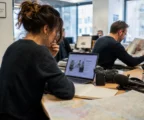 Journaliste dans une rédaction française préparant un sujet territorial avec carnet, micro et carte floue