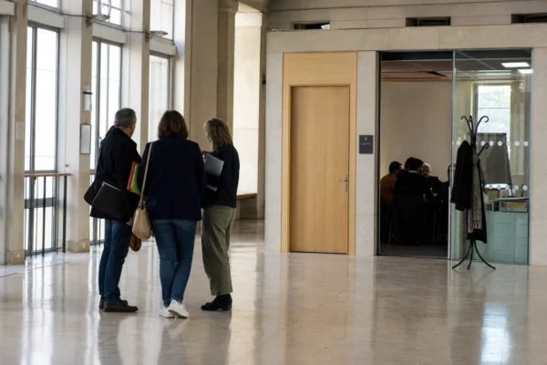 Hall lumineux d’une administration scolaire française, avec une porte de salle d’audition et des personnels anonymes