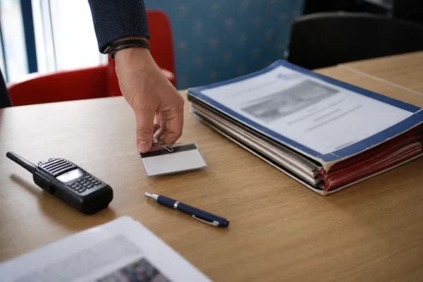 Main posant un badge de presse près d’un dossier institutionnel dans une rédaction politique française