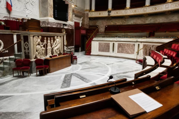Salle parlementaire française vide, marbre blanc et sièges rouges, évoquant le retrait électoral de la gauche en PACA