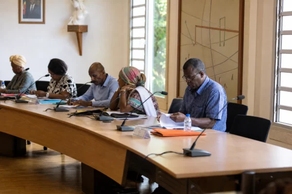 Salle municipale à Mayotte avec chaise vide, micros et dossiers lors d’une réunion locale