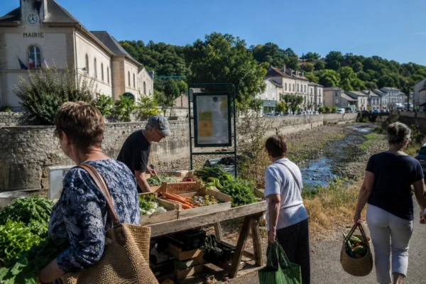 Marché d’une ville française près d’une rivière basse, avec habitants et agriculteur face à la sécheresse