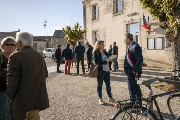 Élus locaux et habitants échangent devant une mairie vendéenne pendant la campagne des élections sénatoriales
