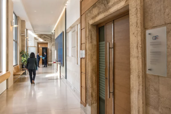 Hall clair d’un régulateur économique français, avec une porte de salle d’audition et des professionnels anonymes