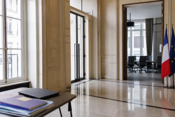 Couloir institutionnel lumineux d’un organisme français de régulation numérique avec ordinateur et dossiers flous.