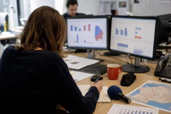 Journaliste préparant un sujet sur la présidentielle 2027 dans une rédaction locale, avec carnet et micro sans logo