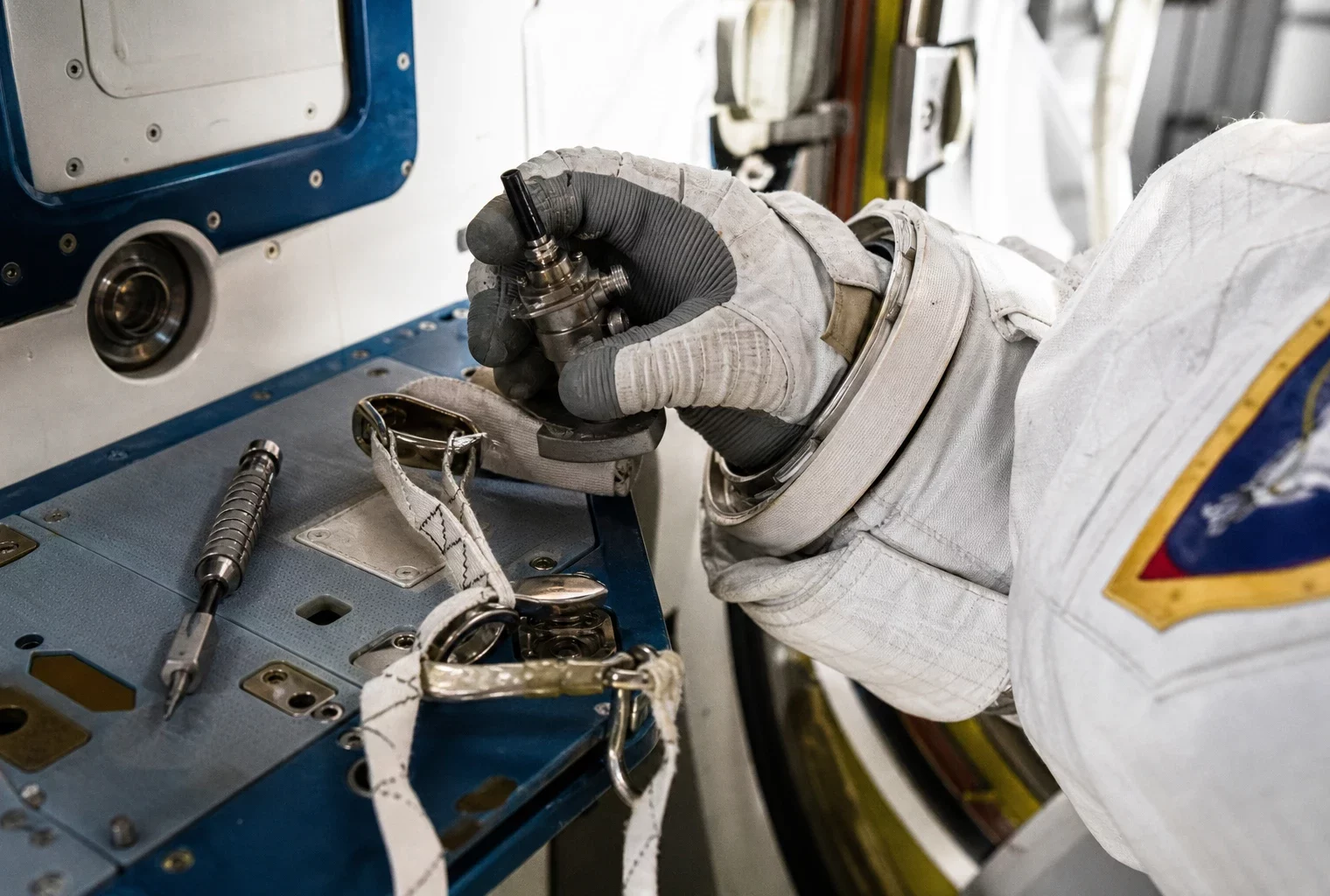 Main gantée vérifiant un connecteur d’antenne et un câble de sécurité lors de la préparation d’une sortie spatiale