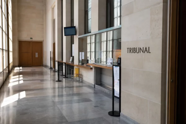 Intérieur lumineux du tribunal de Paris, couloir institutionnel vide avec comptoir d’accueil flou et lumière naturelle.