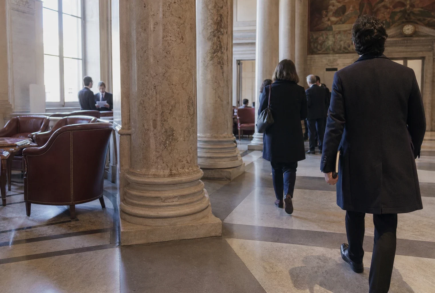 Salle parlementaire française en marbre, avec des journalistes anonymes évoquant les négociations de la gauche