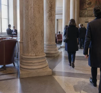 Salle parlementaire française en marbre, avec des journalistes anonymes évoquant les négociations de la gauche
