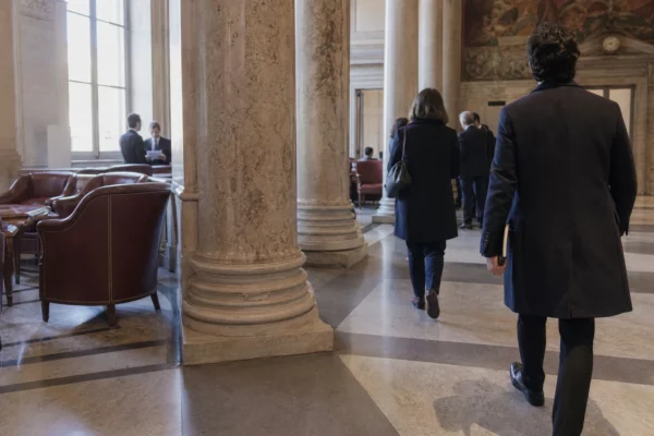 Salle parlementaire française en marbre, avec des journalistes anonymes évoquant les négociations de la gauche