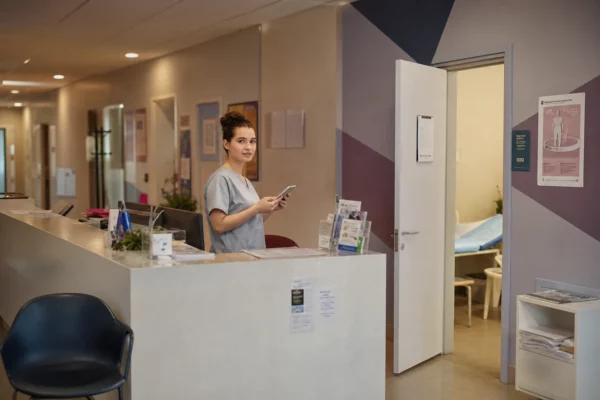 Accueil d’un centre de santé français, couloir de soins au fond, chaise d’attente et porte de cabinet au premier plan.