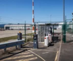 Dispositif de sécurité à l’entrée d’un aéroport français, avec grillage, accès contrôlé et zone technique en arrière-plan.