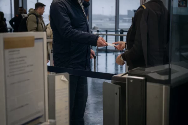 Hall de contrôle d’un aéroport régional français, files d’attente, portiques de sûreté et reflets humides au sol.